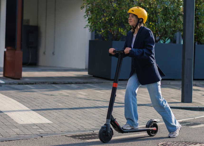 Woman wearing yellow helmet on e-scooter