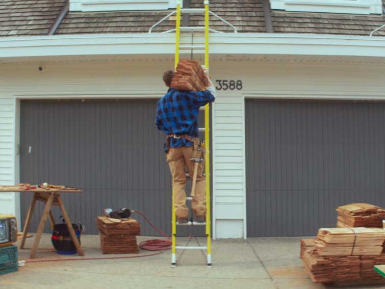 shot of roofer climbing ladder from behind, not wearing harness